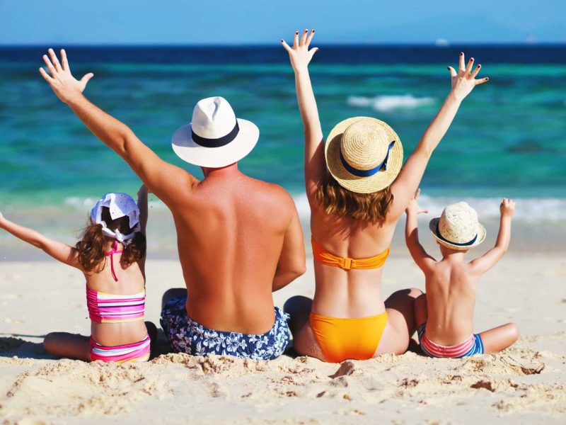 happy family father, mother and children backs on the beach at sea